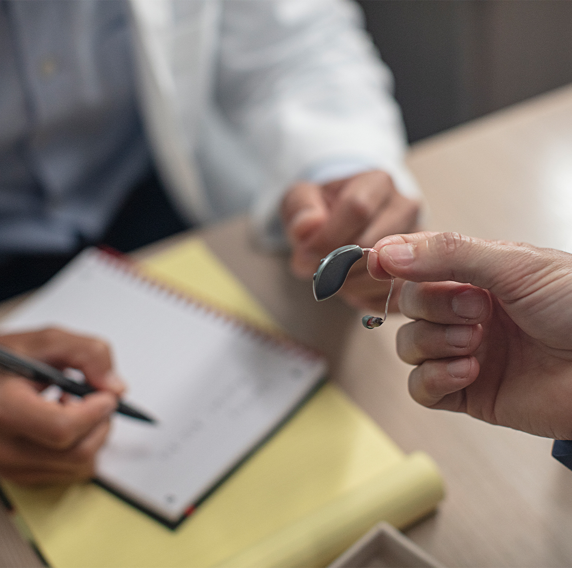 Professional showing patient receiver-in-canal hearing aid