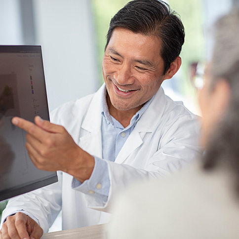 Male audiologist showing patient settings on a computer monitor