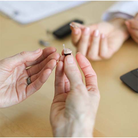 Hands holding hearing aids.