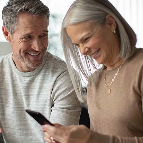 Couple laughing and looking at their phone.
