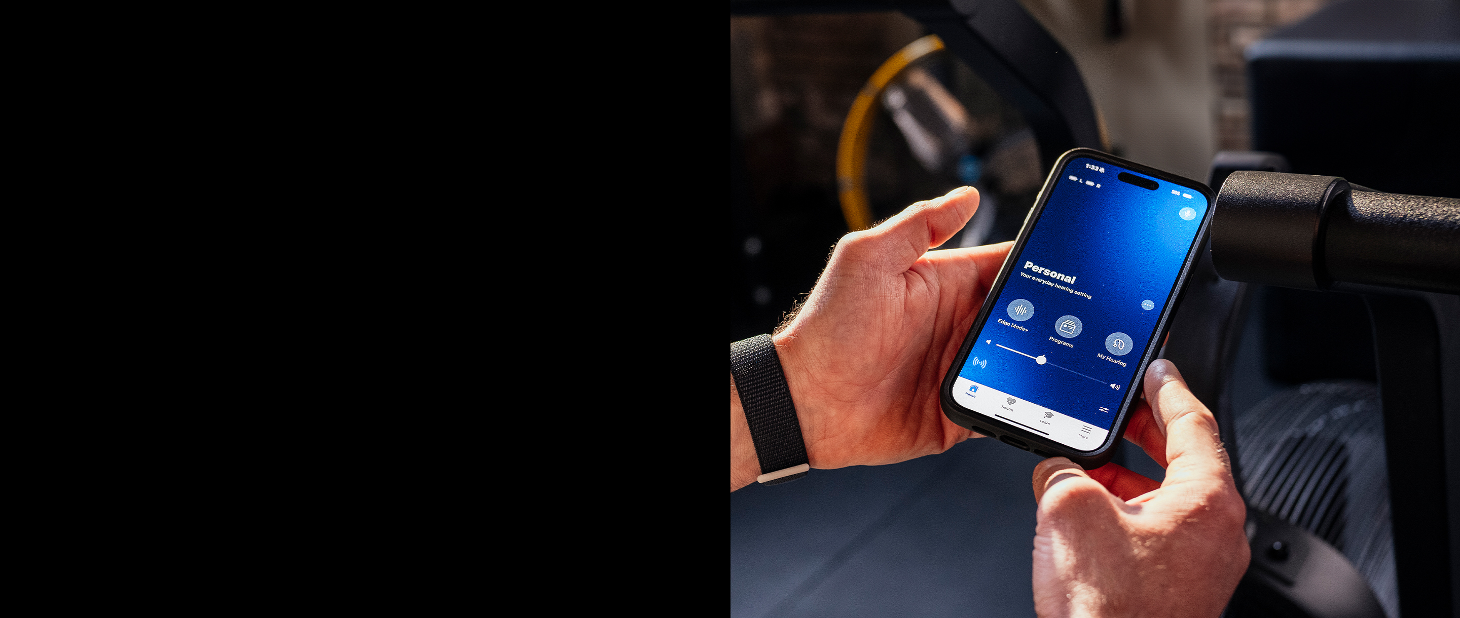 Hands holding a phone with the My Starkey app on the screen.