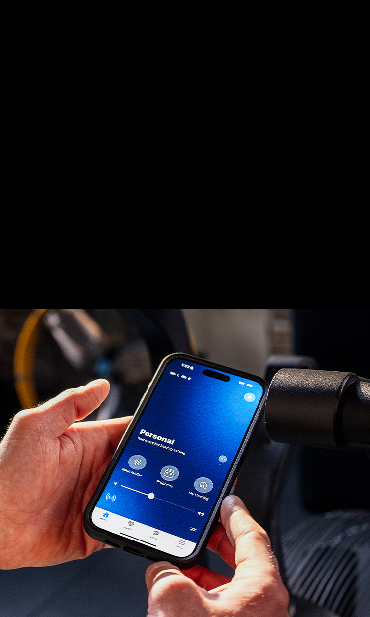 Hands holding a phone with the My Starkey app on the screen.
